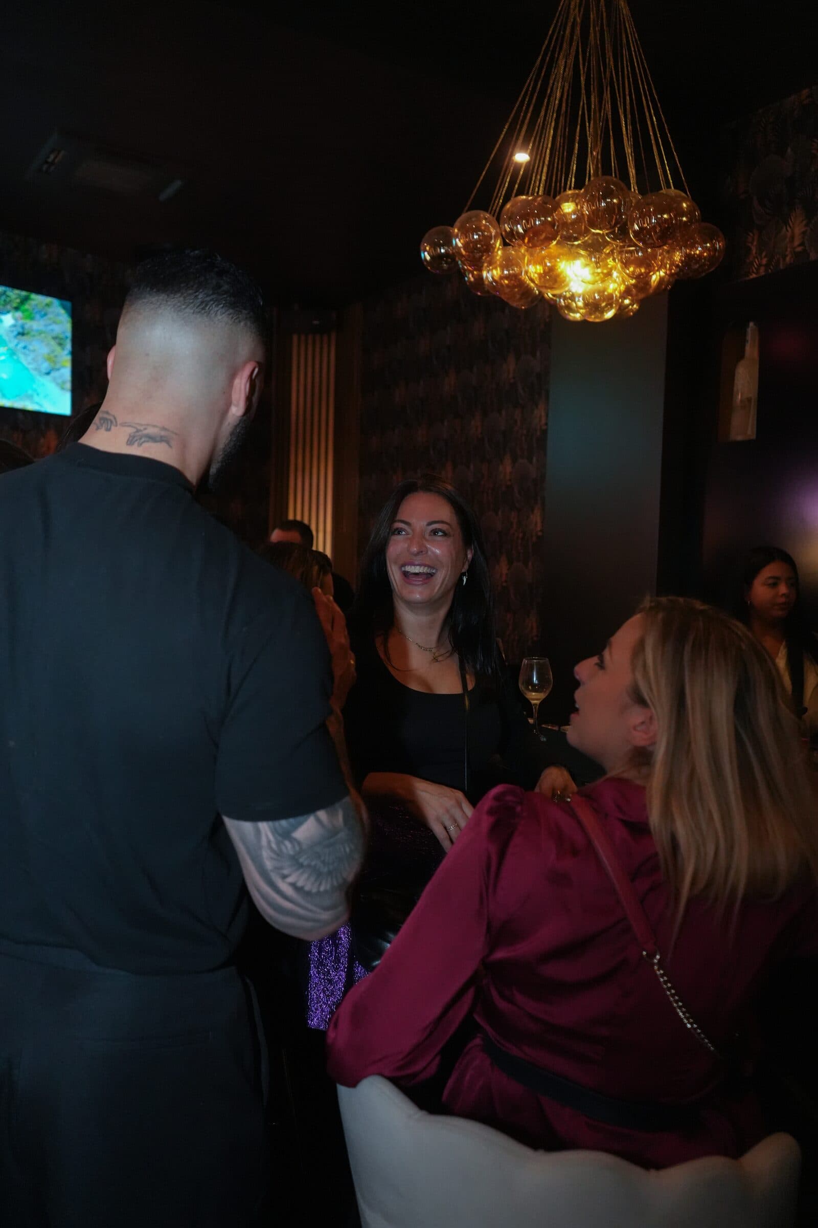 Guests laughing under the bubble chandeliers during a night at La Perla