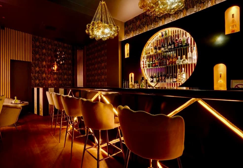 Bar counter with gold arched shelves at La Perla in Paris 17
