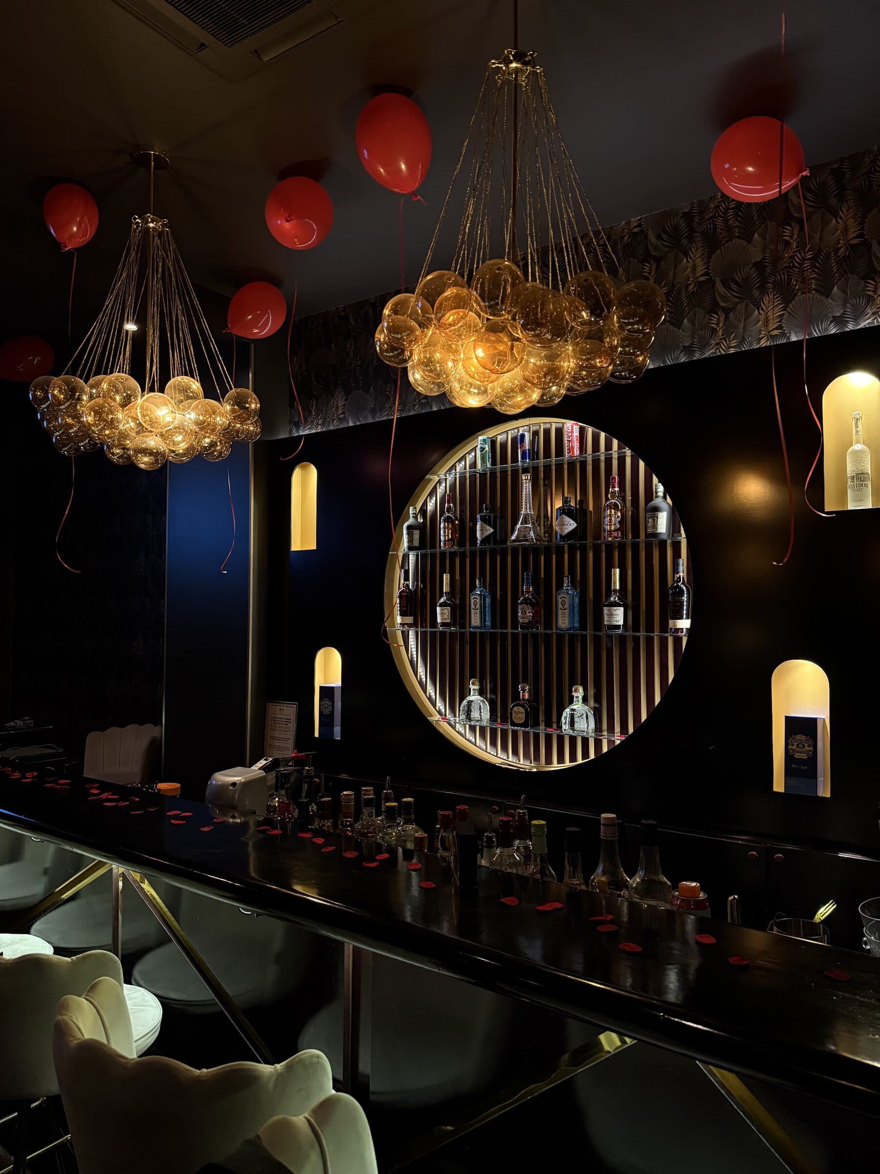 Overhead view of the bar with bubble chandeliers and spirits display at La Perla Paris